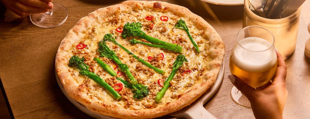 A pizza being eaten with beer